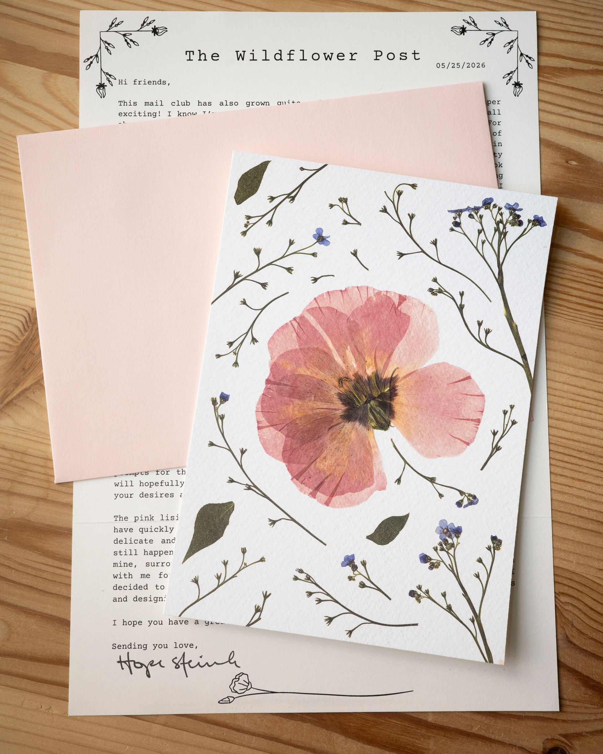 The Wildflower post letter with with a light pink envelope and fine art print of a pressed lisianthus and forget-me-nots.