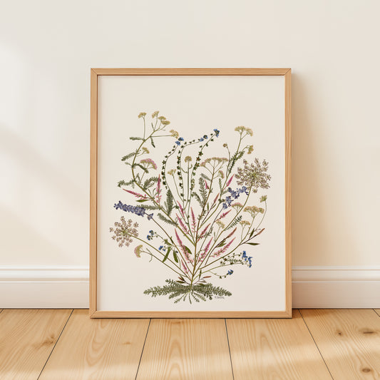 Framed botanical pressed flower art print on a wooden floor with a white wall background