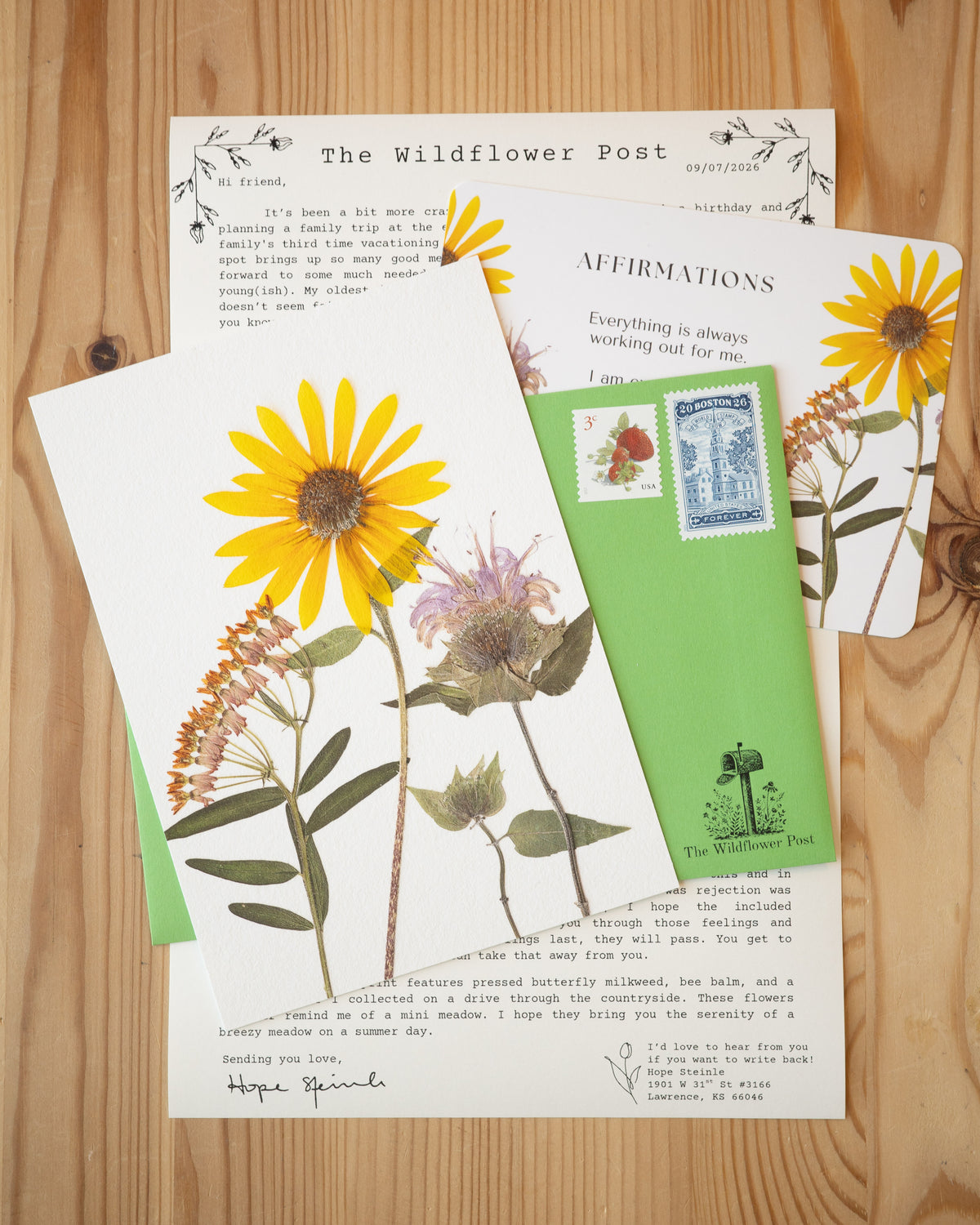 Print of butterfly milkweed, wild sunflower, and bee balm on table with letter and affirmation card. 